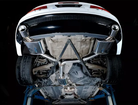 Onderaanzicht van een witte Audi A4 op een hefplatform, met daarop een Simons roestvrijstalen Duplex L+R sportuitlaat met 1x100 mm uitlaatpijpen. De foto benadrukt het uitlaatsysteem, inclusief pijpen en achterdemper.